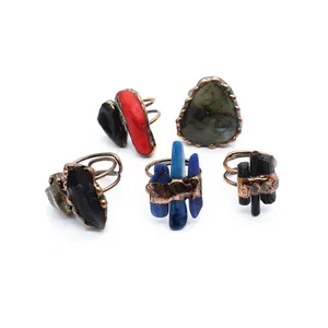 Collection of rustic handmade open rings with various colorful raw natural gemstones.