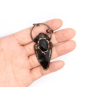 Detalle del colgante de punta de flecha con piedra negra y borde de cobre rústico