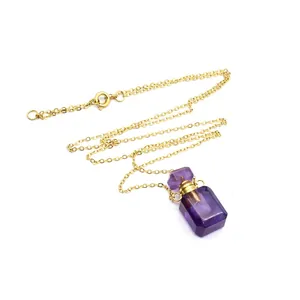 Détail d'un pendentif flacon de parfum en cristal violet sur une fine chaîne dorée