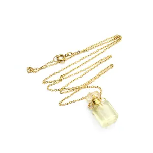 Gros plan détaillé d'un collier en chaîne dorée avec un pendentif flacon de parfum en cristal jaune.
