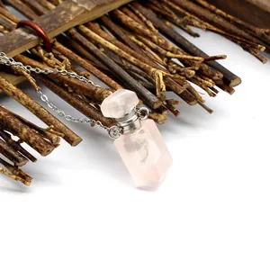 Gros plan d'un pendentif flacon de parfum en quartz rose sur une chaîne argentée