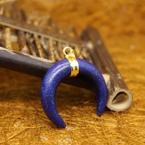 Lapis lazuli crescent horn pendant with gold-plated clasp on a natural rustic background