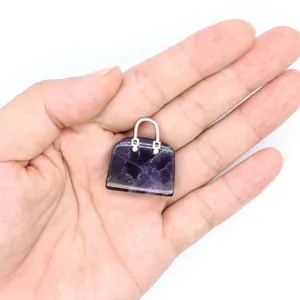 Detailansicht eines lila Naturstein-Handtaschenanhängers auf der Handfläche.