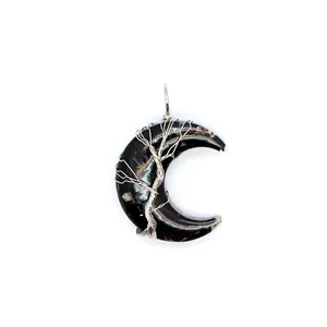 Gros plan d'un pendentif en croissant de lune noir avec arbre de vie en fil d'argent