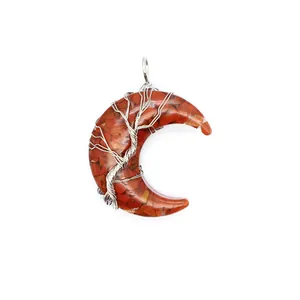 Gros plan d'un pendentif lune avec des pierres naturelles rouges et un arbre de vie en fil