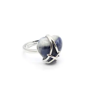 Detail shot of a silver heart-shaped stone ring with a cage-style setting design.