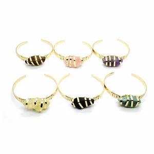 Sei bracciali aperti placcati oro con una varietà di pietre naturali grezze colorate.