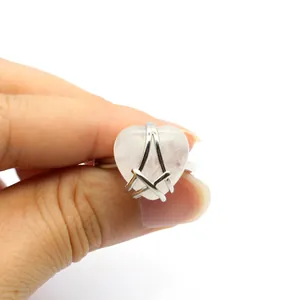 Detail showing a silver-tone ring with a heart-shaped pink stone held by hand