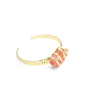 Vista dettagliata di un bracciale rigido placcato oro con pietra naturale grezza