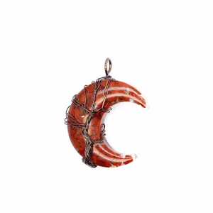 Détail d'un pendentif lune en résine avec pierres rouges et fil de cuivre enroulé.