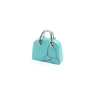 Detailansicht eines Handtaschen-Anhängers aus Türkis mit silbernen Griffen und Textur.