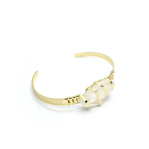 Dettaglio di un bracciale a fascia placcato oro 24K con incastonatura in quarzo bianco.