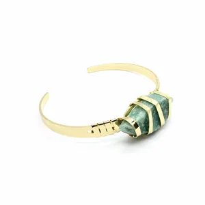 Dettaglio di una pietra naturale verde grezza incastonata in un bracciale rigido placcato oro