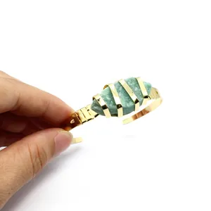 Primo piano di un bracciale rigido placcato oro con pietra naturale verde grezza
