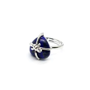 Macro view of heart-shaped blue natural stone ring with elegant silver ribbon bow wrap.
