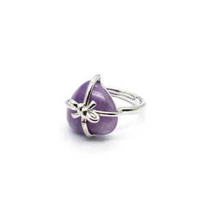 Close-up of heart-shaped purple stone ring with elegant silver bow-knot cage design