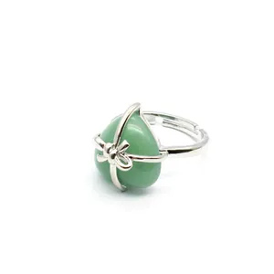 Detailed view of an elegant heart-shaped green stone ring with a silver ribbon bow design