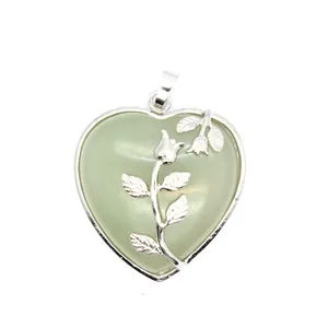 Vue détaillée d'un pendentif en forme de cœur avec pierre verte et décor de rose argentée