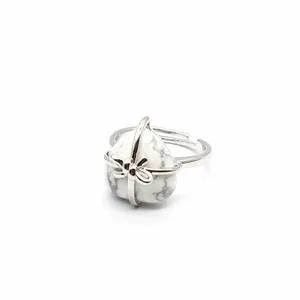 Detailed shot of a heart-shaped white turquoise ring with a delicate silver bow accent