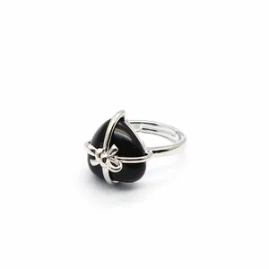 Detail shot of a black heart-shaped natural stone ring with a silver bow design