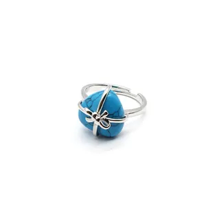 Close-up of an elegant silver ring with a heart-shaped turquoise stone and bow detail
