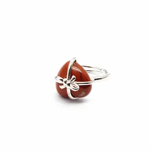 Detailed view of a red heart-shaped natural stone ring wrapped in silver ribbon bow design