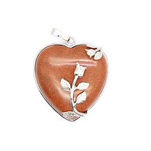 Gros plan d'un pendentif en forme de cœur en pierre de soleil avec détail de rose en argent massif
