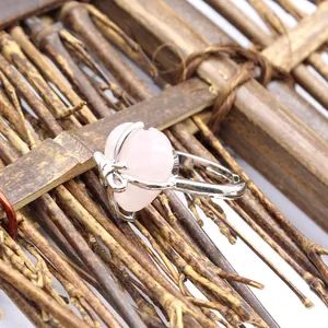 Close-up detail shot of a pink rose quartz heart ring featuring a silver bow accent.