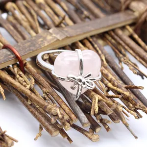 Macro detail of an ins style heart-shaped rose quartz ring with a silver bow wrap.