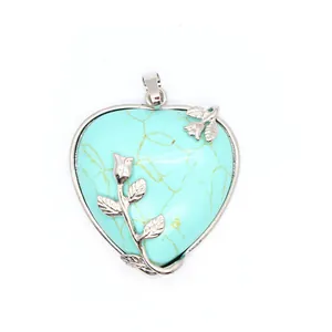 Vue détaillée d'un pendentif coeur en turquoise avec des accents de branches de roses.