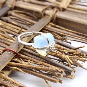 Close-up of silver-tone adjustable ring with a heart-shaped opalite stone and bow detail