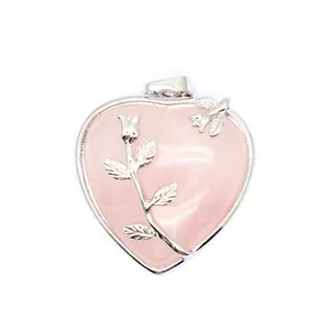 Gros plan d'un pendentif en quartz rose en forme de cœur avec détail de rose argenté.