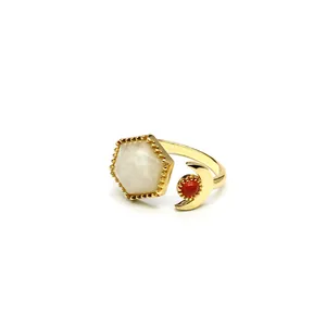 Detail shot of a gold open ring with hexagonal white crystal and red moon stone accents.