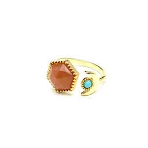 Detailed view of gold open ring with hexagonal orange stone and turquoise moon