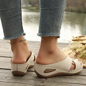 Detailansicht von beigen Keilsandalen mit gekreuzten Riemen und weicher Sohle im Freien