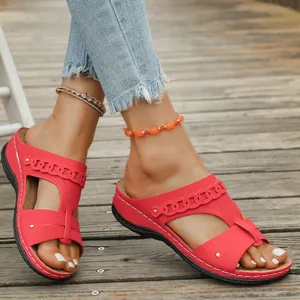 Detail view of stylish red wedge sandals with cutout straps on a sunlit wooden deck