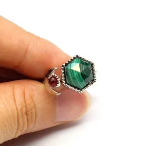 Close-up of a silver open ring featuring a green hexagonal malachite stone and red moon detail.