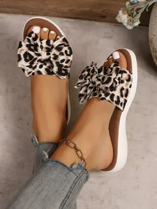 Close-up of leopard print bow slide sandals worn with denim and an anklet