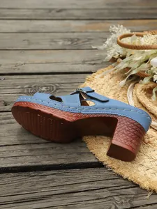Detaillierte Nahaufnahme einer blauen Pantolette mit Blockabsatz auf Holzuntergrund