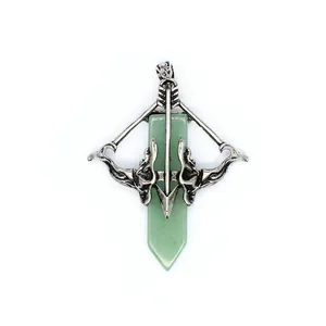 Detailed macro shot of vintage Cupid's bow and arrow pendant with green crystal point