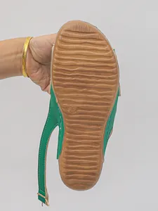 Detail view of the brown anti-slip wavy outsole on green platform wedge sandal