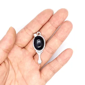 Close-up of a vintage magic mirror pendant with sparkling blue goldstone stone on a hand