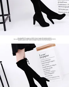 Close-up of black suede over-the-knee boots with high block heels and sleek design