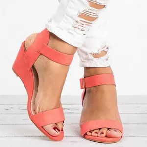 Detailed view of coral suede wedge sandals featuring an adjustable ankle strap and open toe