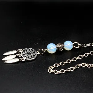 Close-up of bohemian dreamcatcher pendant with opal-like beads and feathers on black