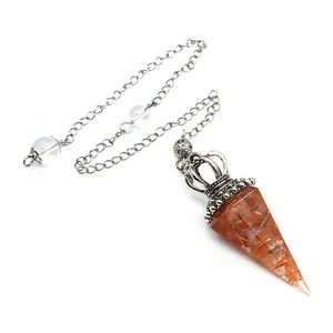 Close-up of resin pendulum with orange crystal chips and silver crown cap for dowsing