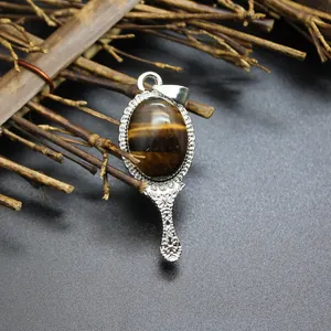 Detailed view of an ornate mirror-shaped pendant featuring a polished tiger eye stone