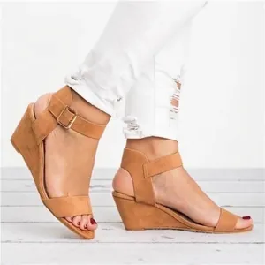 Elegant tan faux suede wedge sandals featuring a stylish ankle strap and gold buckle