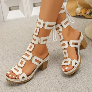 Elegant white hollow-out caged sandals with chunky heels and gold metallic accents.