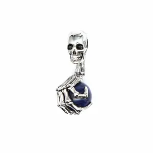 Detailansicht eines silbernen Totenkopf-Anhängers mit einer Skeletthand und blauem Stein